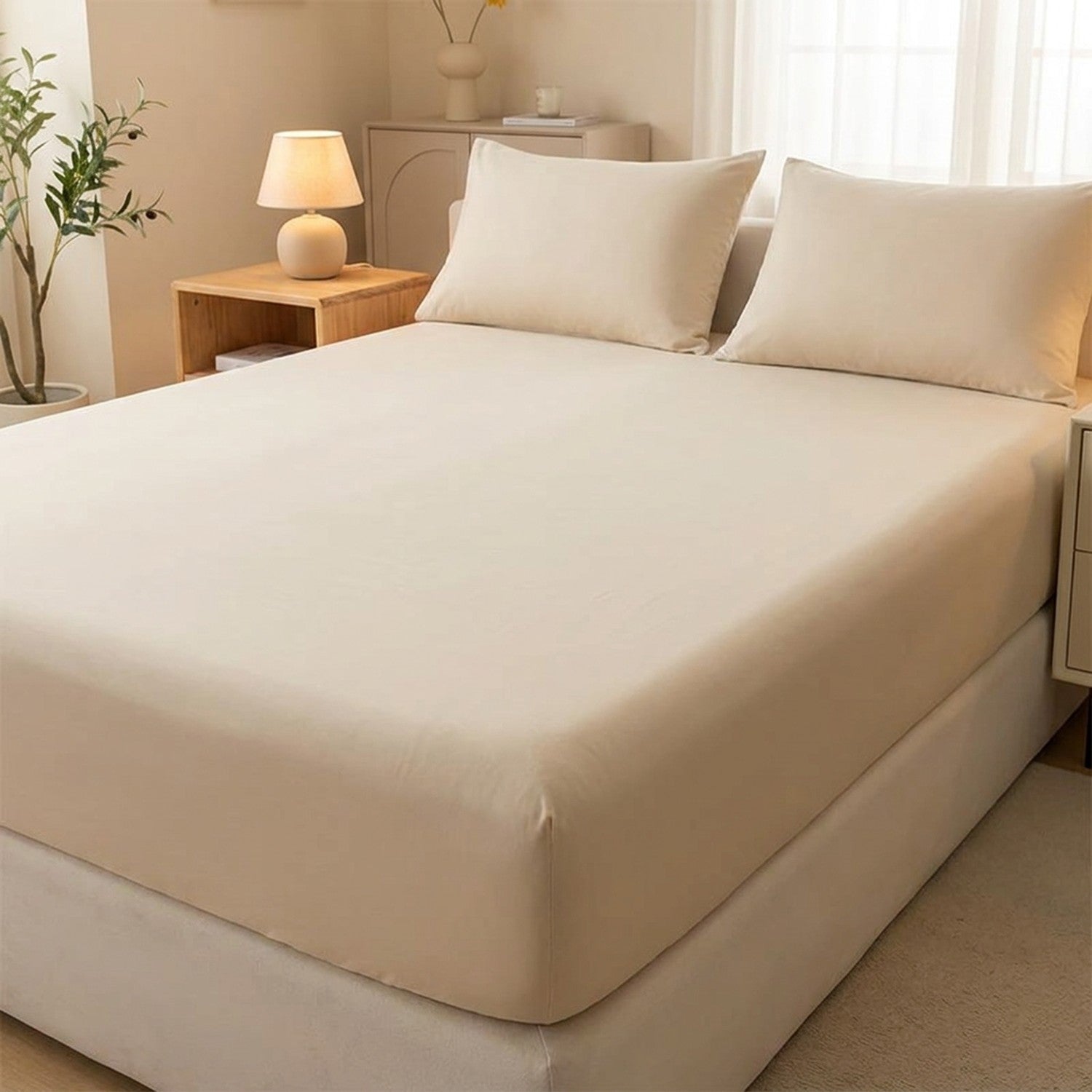 Drap-housse délavé beige tendu sur un matelas avec oreillers assortis dans une chambre neutre