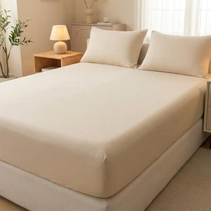 Drap-housse délavé beige tendu sur un matelas avec oreillers assortis dans une chambre neutre