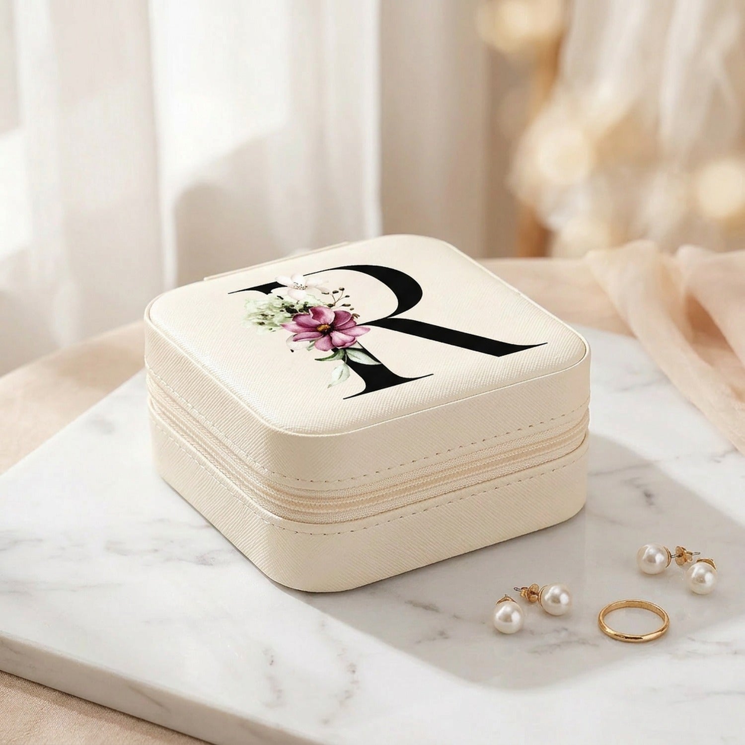 Boîte à bijoux de voyage en cuir PU avec initiale florale posée sur marbre blanc avec lumière naturelle