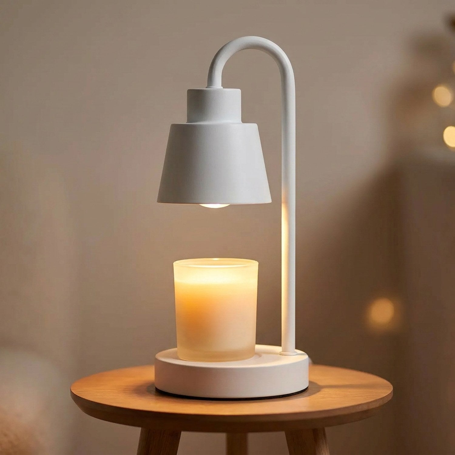 Lampe chauffe-bougie blanche allumée sur une petite table ronde en bois