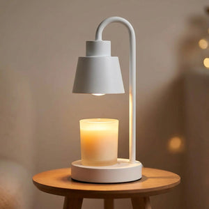 Lampe chauffe-bougie blanche allumée sur une petite table ronde en bois