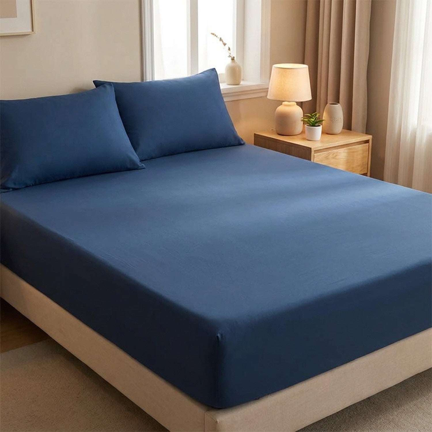 Drap-housse délavé bleu foncé tendu sur un matelas avec oreillers assortis dans une chambre cosy