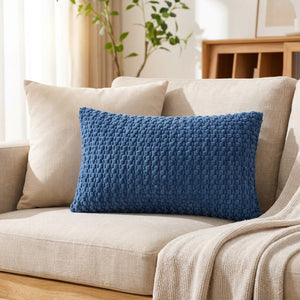 housse de coussin rectangulaire en maille texturée bleu sur un canapé en lin