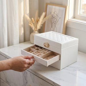 Main ouvrant un tiroir de la boîte à bijoux montrant le rangement intérieur