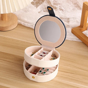 Boîte à bijoux ronde ouverte avec bijoux posés dans les compartiments
