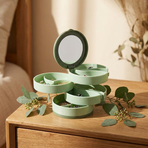Boîte à bijoux rotative verte ouverte sur table de nuit avec eucalyptus