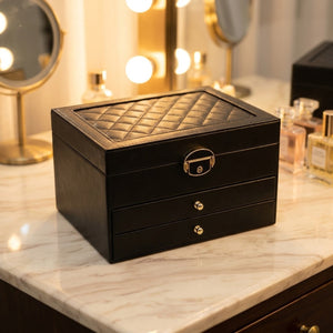 Boîte à bijoux multicouche en cuir noir avec motif matelassé et fermoir doré sur coiffeuse élégante