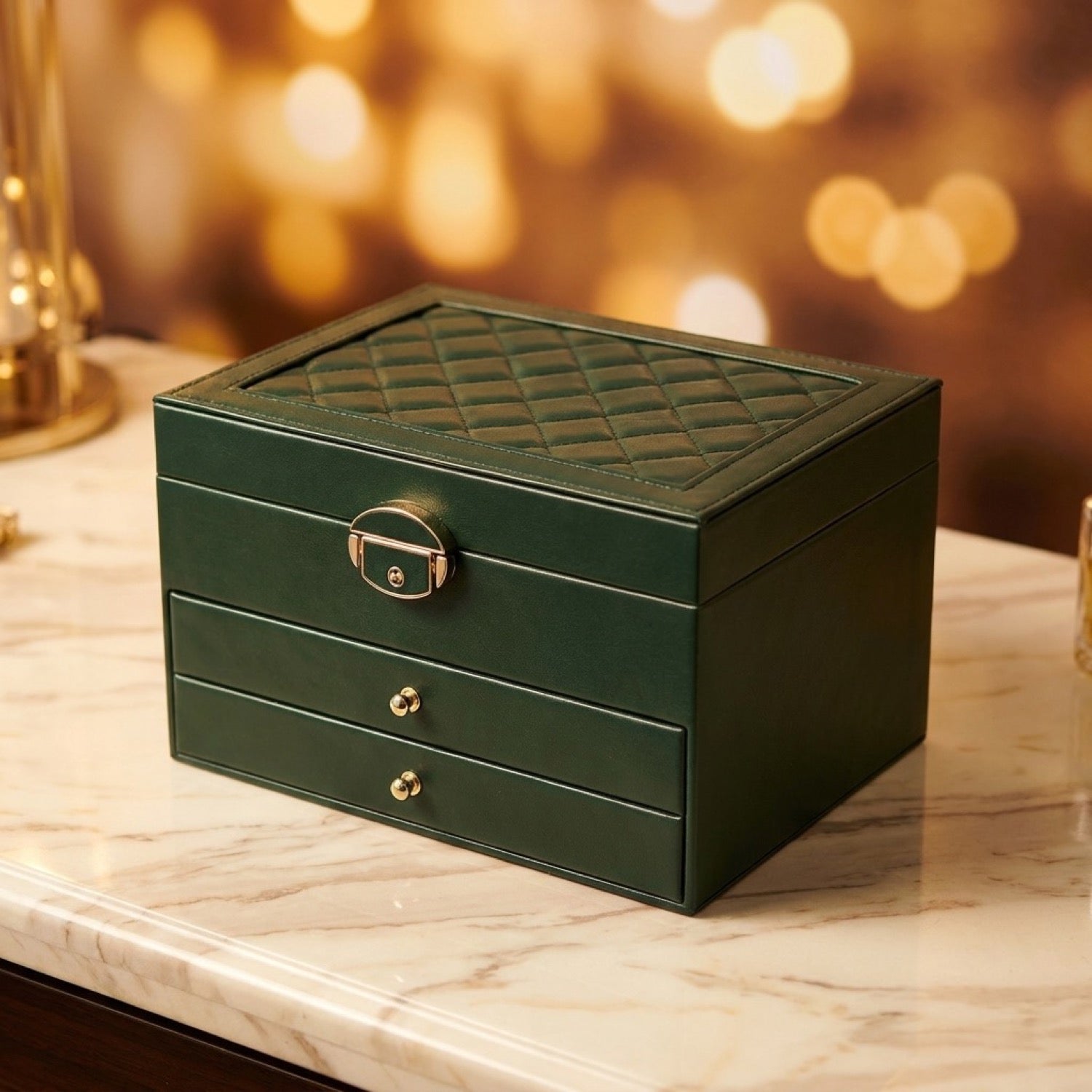 Boîte à bijoux multicouche en cuir vert foncé avec motif matelassé et fermoir doré sur marbre