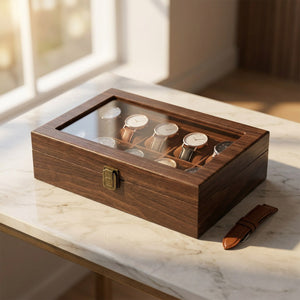 Boîte à montres en bois fermée sur une console en marbre avec un bracelet en cuir à côté