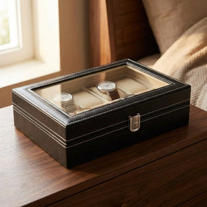 Boîte à bijoux et montres noire à dessus vitré et intérieur velours beige posée sur une commode en bois