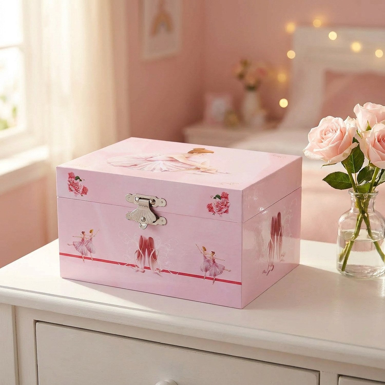 Boîte à musique ballet rose fermée sur coiffeuse avec roses dans chambre de fille