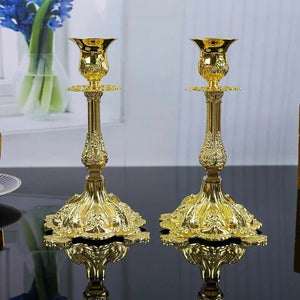 Vue de face de deux bougeoirs en métal doré baroque sur surface réfléchissante