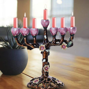 Bougeoir arbre fleuri avec 7 bougies roses allumées posé sur table bois