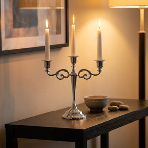 Bougeoir chandelier argent sur console en bois sombre avec bougies en soirée