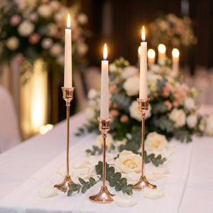 Kit de 3 bougeoirs dorés élancés sur table de mariage avec roses blanches et bougies allumées