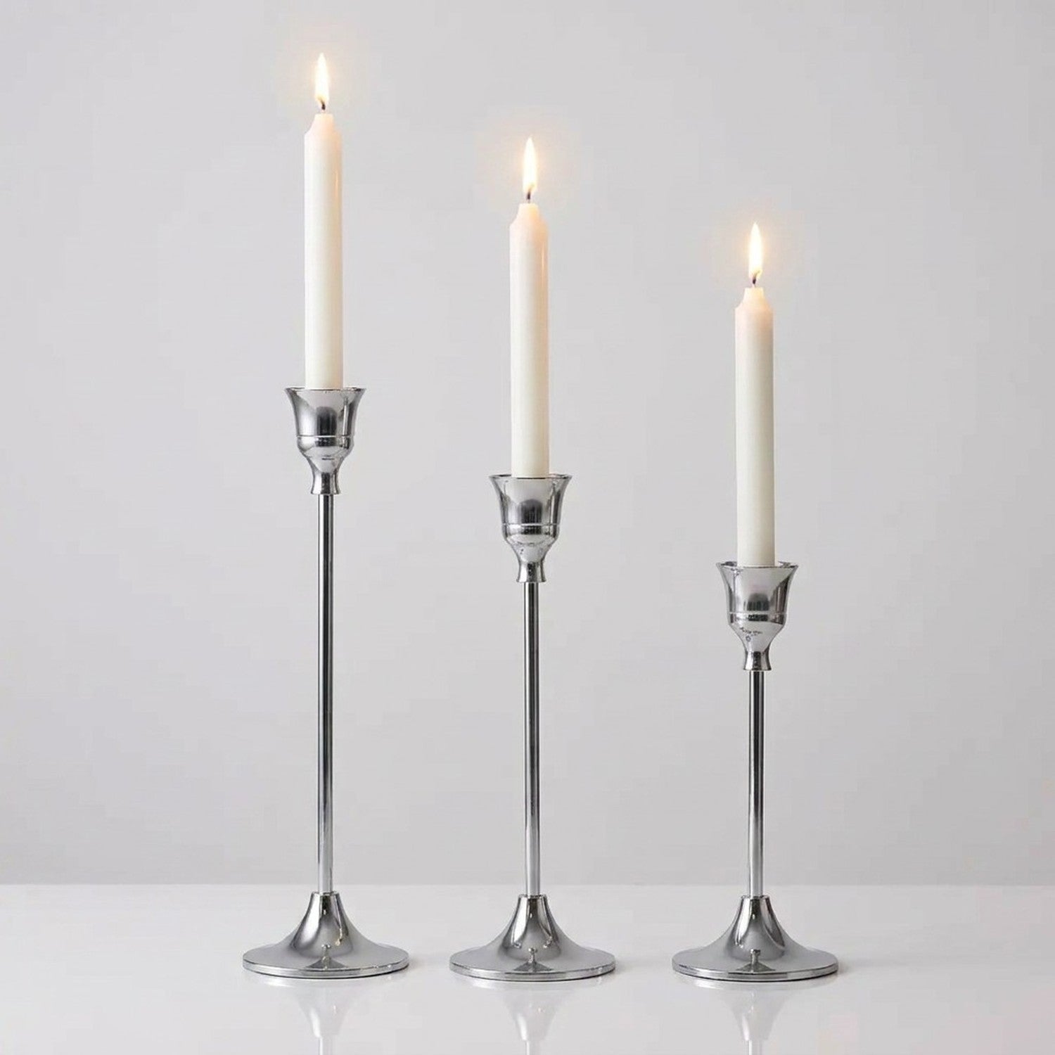 Kit 3 bougeoirs métal argent chrome élancé avec bougies allumées fond gris