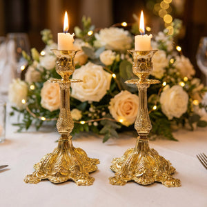 Deux bougeoirs dorés sur table de mariage avec roses blanches et lumières d'ambiance