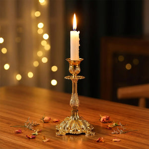 Bougeoir en métal doré baroque avec bougie allumée sur table en bois ambiance romantique