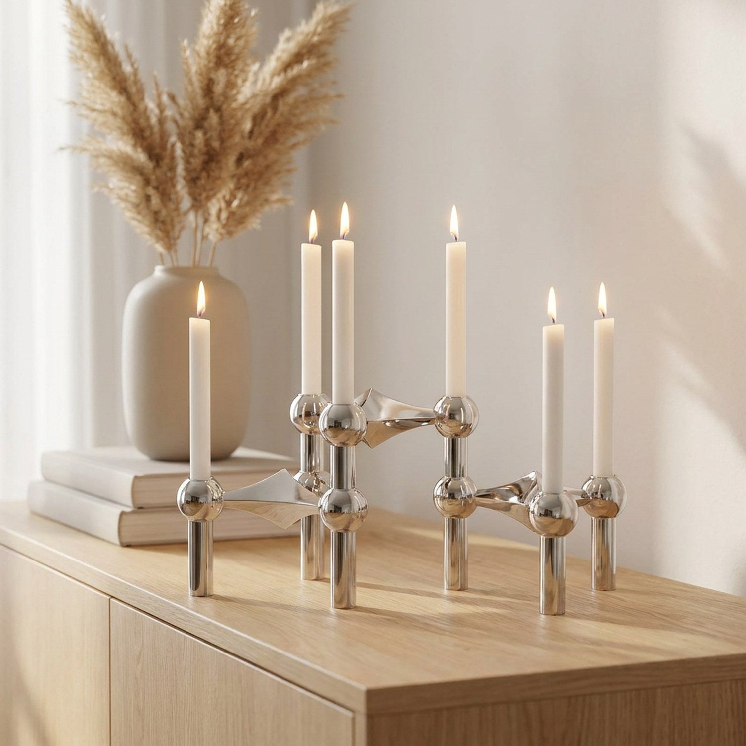 Bougeoir moléculaire argenté avec bougies allumées sur une console en bois scandinave