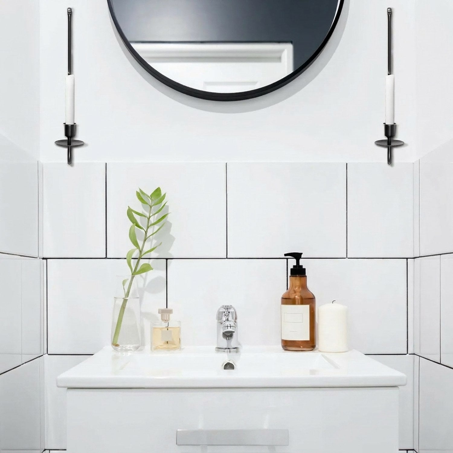 Deux bougeoirs muraux fer forgé flanquant un miroir rond dans salle de bain
