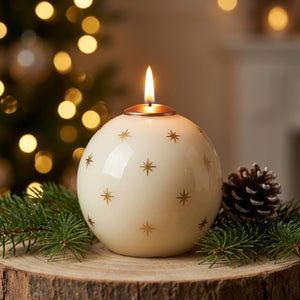 Bougie parfumée de Noël blanche en forme de boule avec étoiles dorées allumée