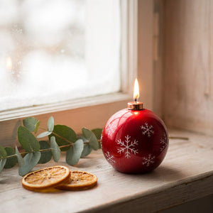 Bougie parfumée de Noël rouge allumée sur un rebord de fenêtre avec eucalyptus