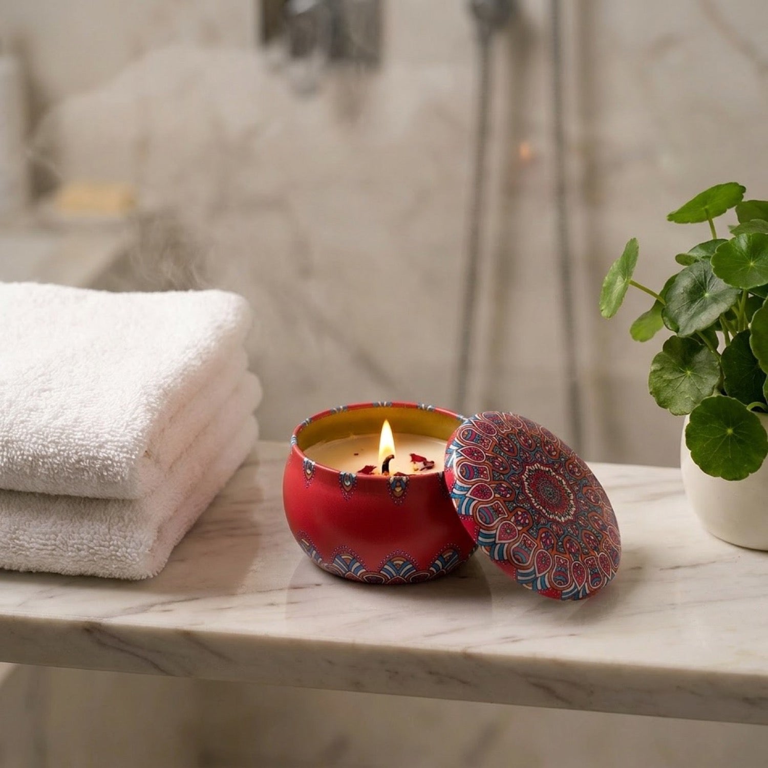 Bougie parfumée en cire de soja allumée dans sa boîte mandala rouge posée sur étagère de salle de bain en marbre