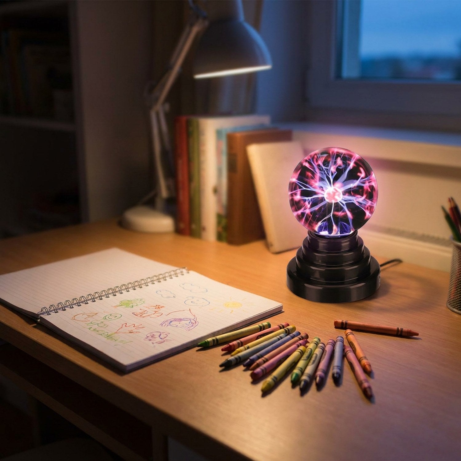 Boule plasma allumée sur un bureau d'enfant entourée de crayons de couleur