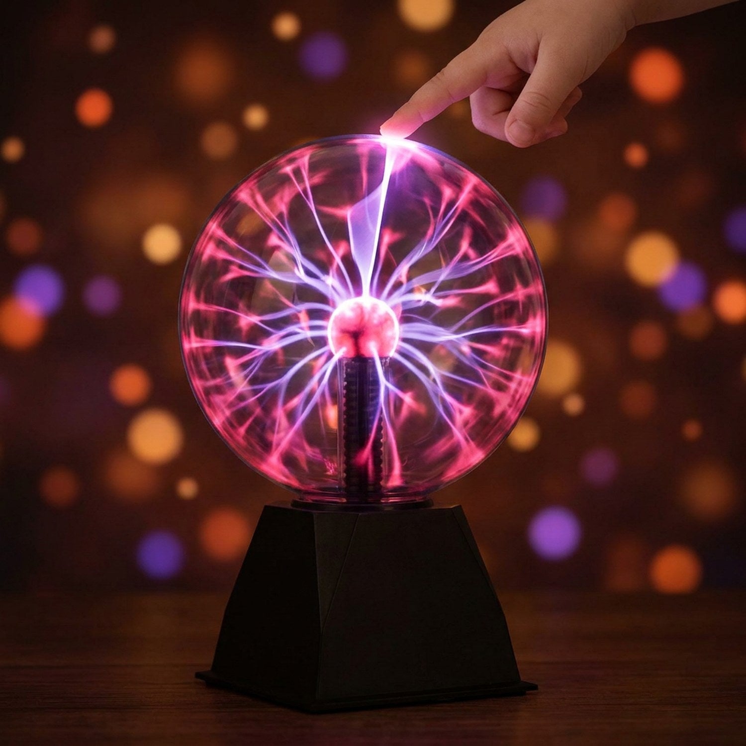 Boule de verre plasma illuminée de filaments roses touchée du doigt sur fond sombre