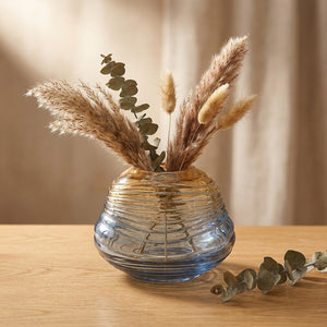 Vase en verre dégradé forme boule avec branches séchées sur surface bois