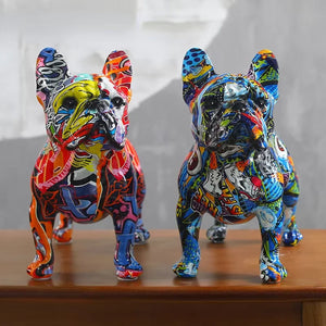 Deux statues bouledogue français en résine avec motifs graffiti multicolores posées sur une table en bois