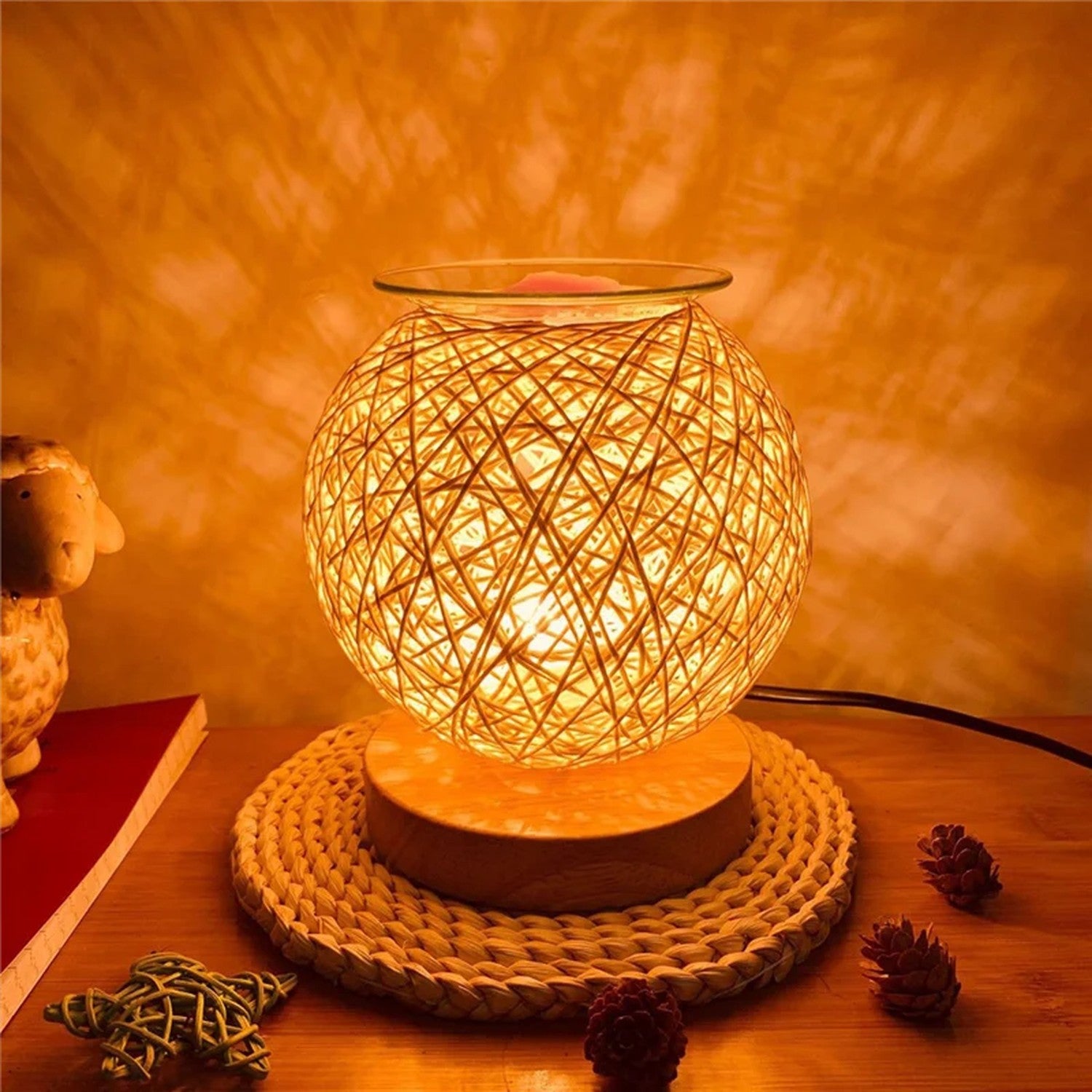 Brûle-parfum en rotin allumé diffusant une lumière chaude et de doux motifs sur un mur clair
