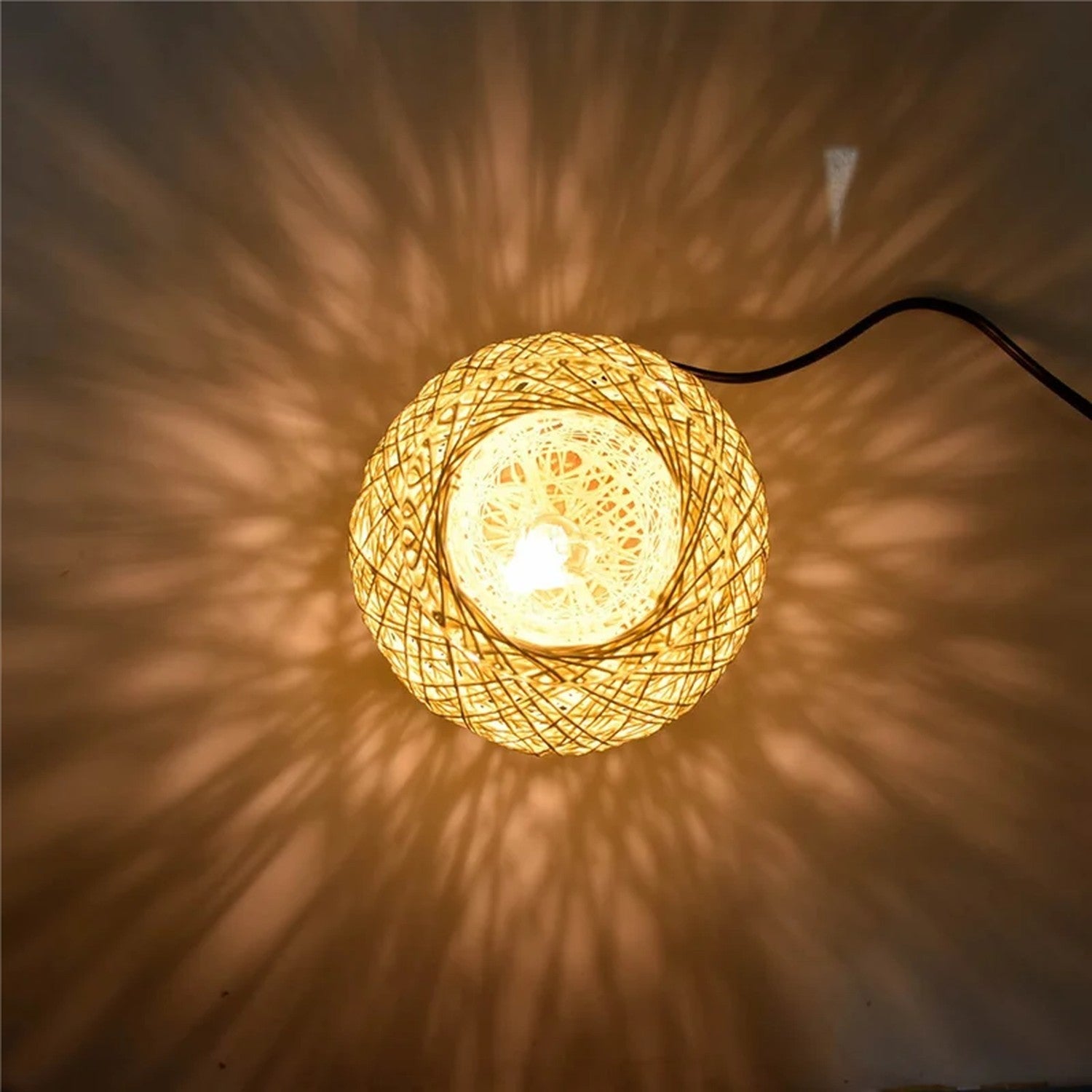 Boule en rotin tressé allumée projetant de délicats motifs lumineux tout autour dans une pièce sombre
