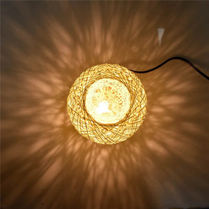 Boule en rotin tressé allumée projetant de délicats motifs lumineux tout autour dans une pièce sombre