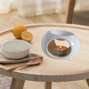 Brûle-parfum céramique blanc sur table en bois avec citrons et bougie allumée