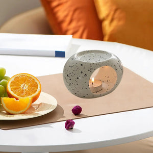 Brûle-parfum céramique finition mouchetée sur table à manger avec fruits et verdure