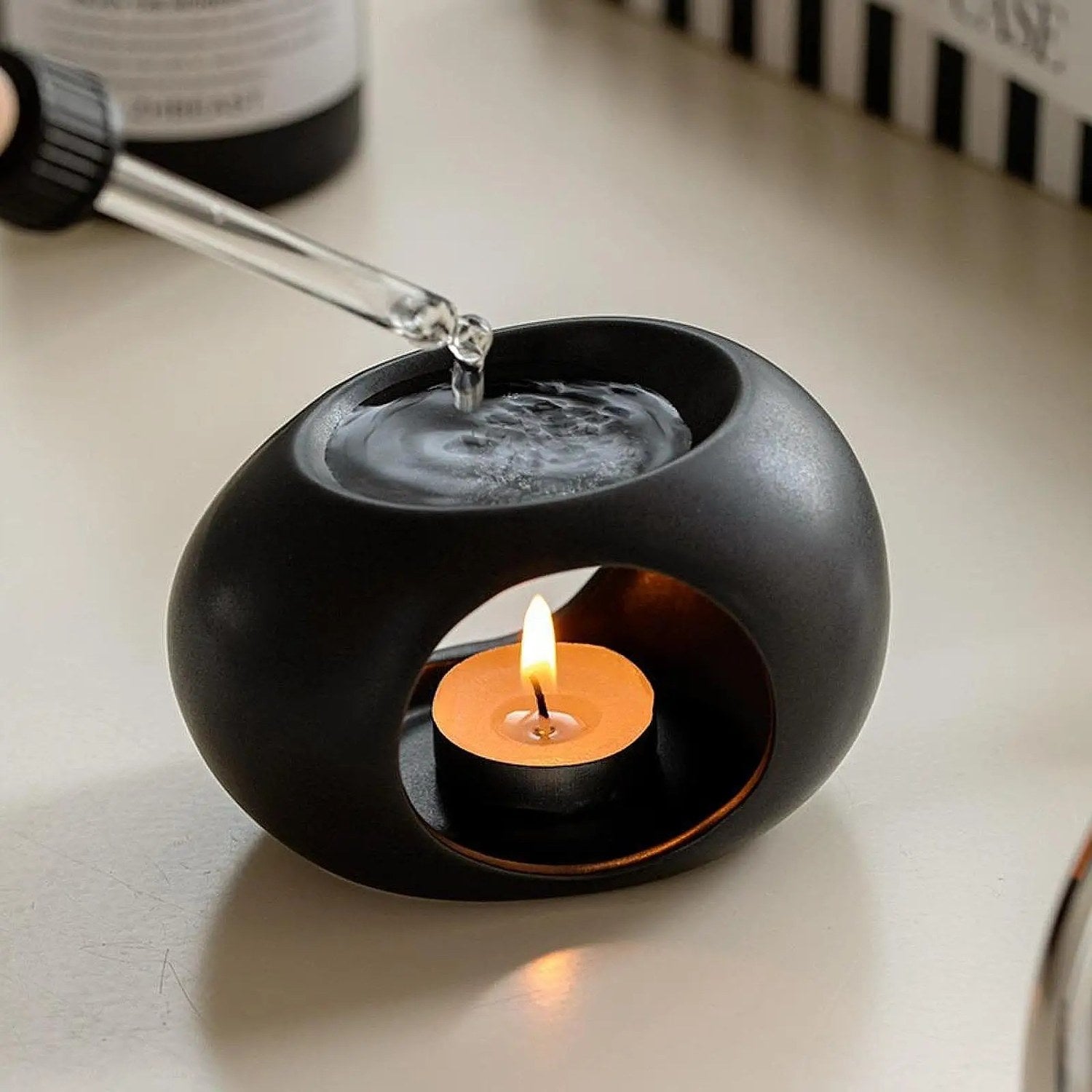 Brûle-parfum céramique noir avec pipette ajoutant de l'huile essentielle