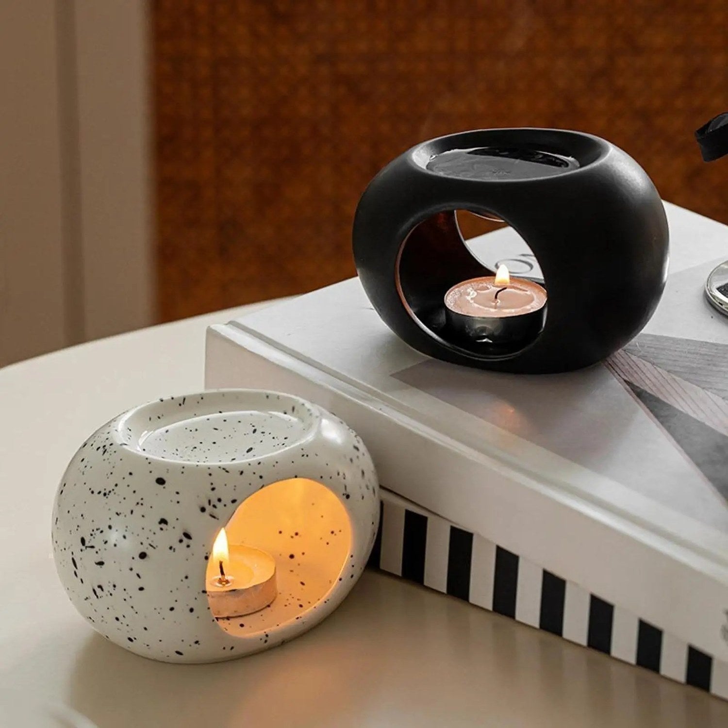 Brûle-parfums céramique noir et moucheté posés sur des livres, ambiance chaleureuse