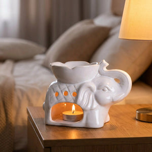 Brûle-parfum éléphant allumé sur une table de chevet dans une chambre chaleureuse avec lampe