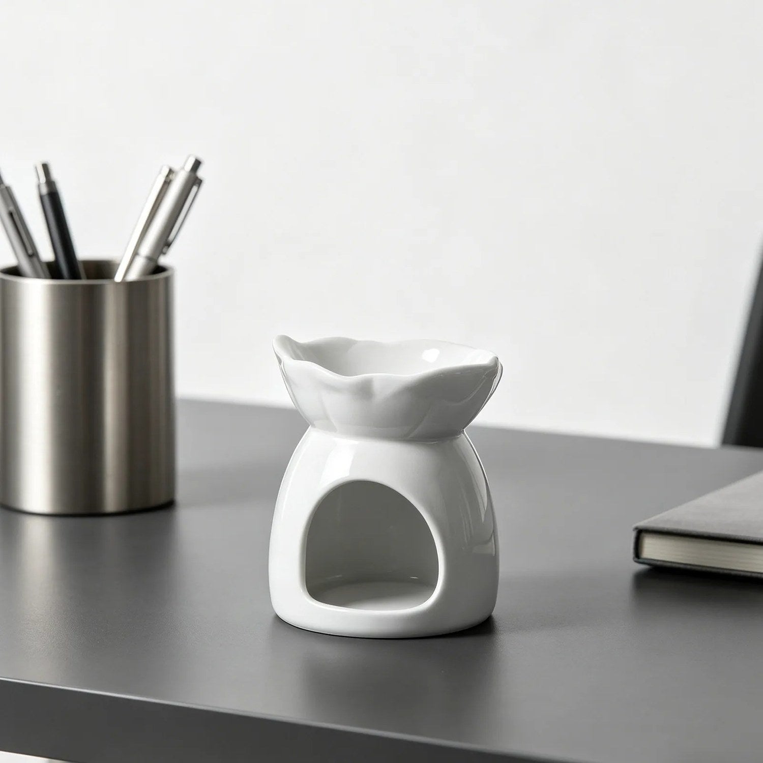 Brûle-parfum céramique blanc posé sur un bureau avec pot à crayons