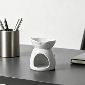Brûle-parfum céramique blanc posé sur un bureau avec pot à crayons
