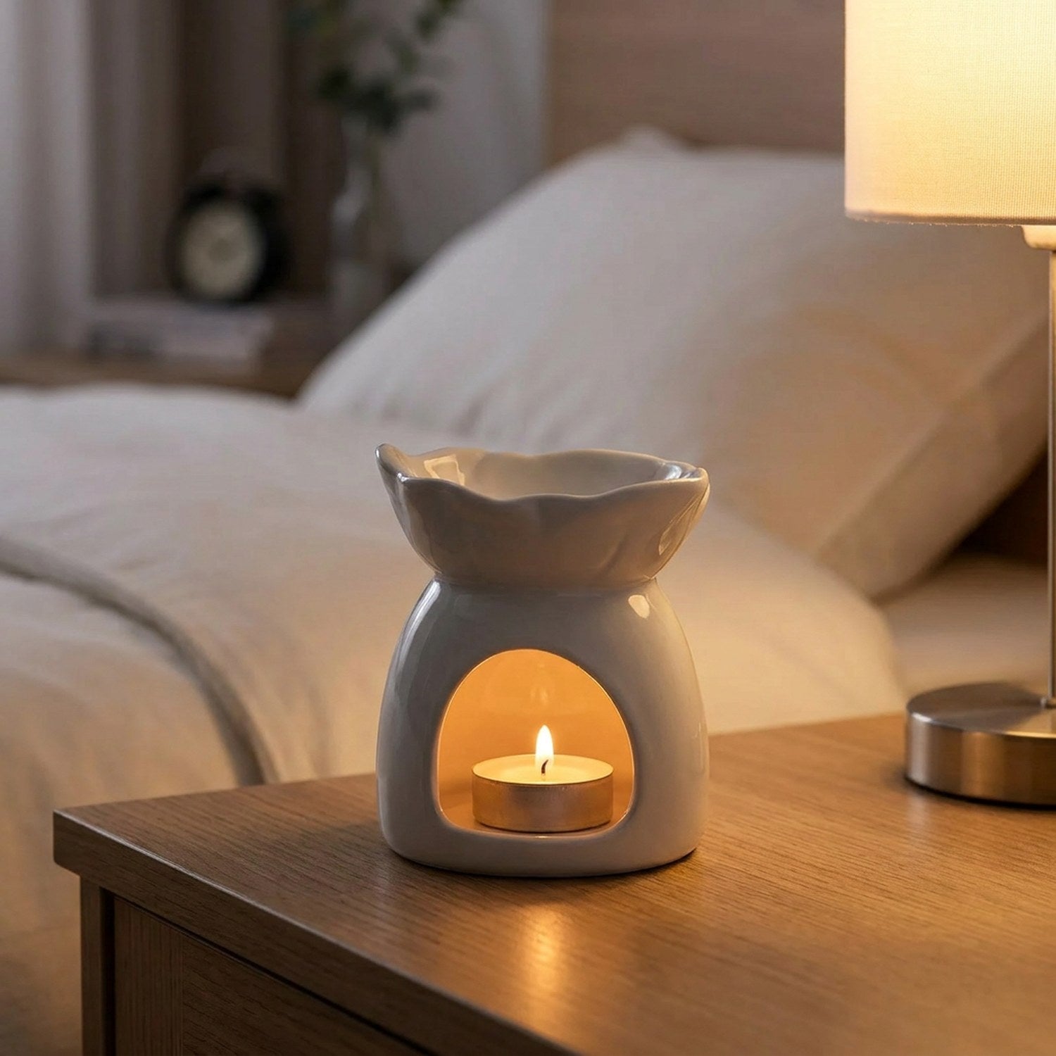 Brûle-parfum céramique blanc allumé sur une table de chevet dans une chambre chaleureuse