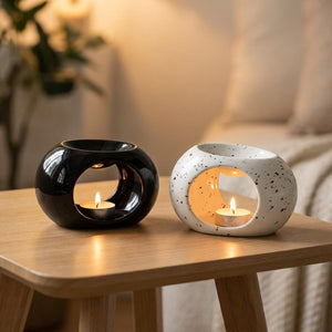 Brûle-parfums céramique noir et moucheté allumés sur table bois ambiance cosy
