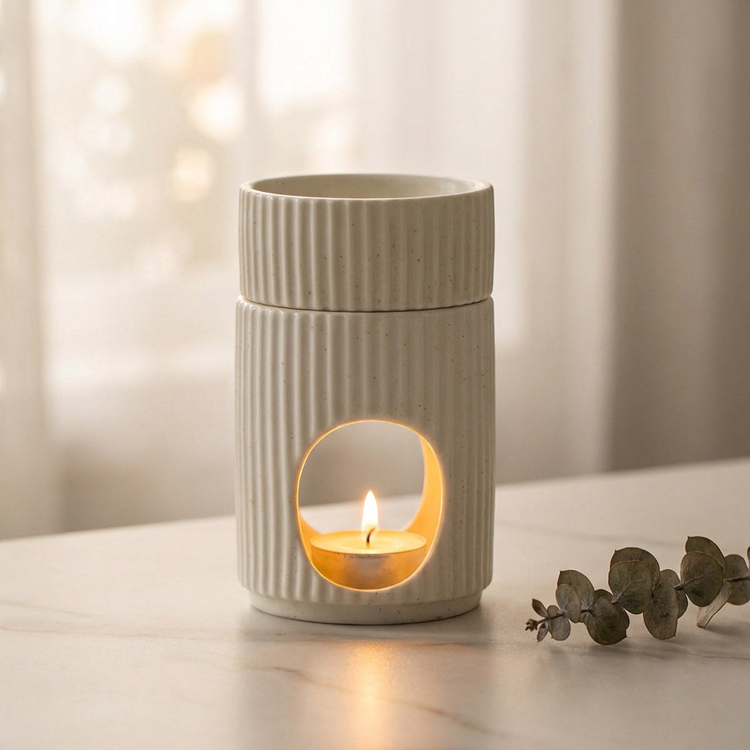 Brûleur d'encens céramique blanc sur marbre avec eucalyptus et bougie allumée