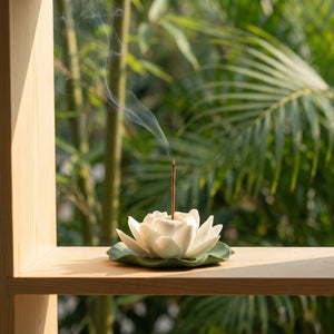 Brûleur d'encens lotus en céramique blanche sur étagère en bois avec plante verte bambou