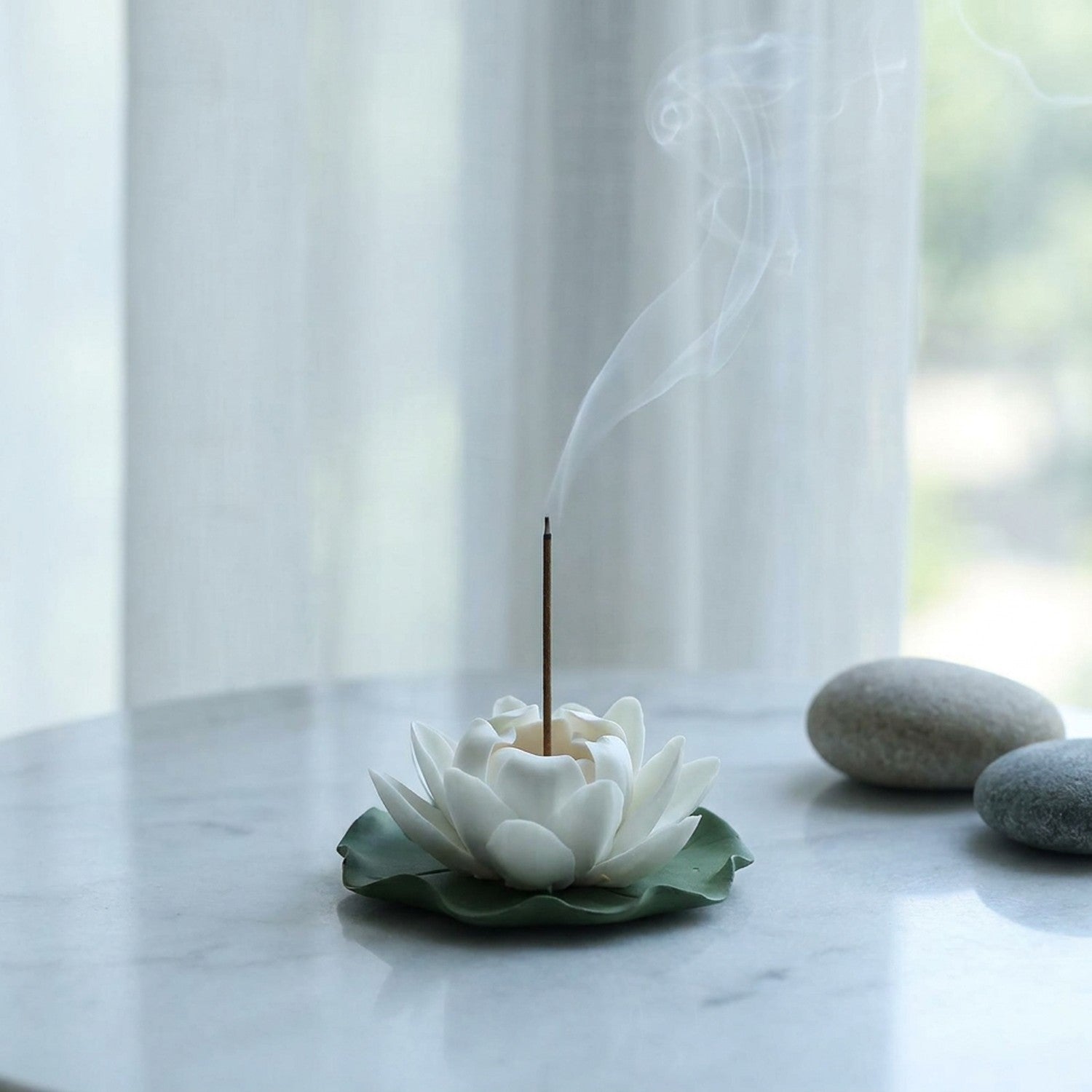 Brûleur d'encens lotus céramique sur marbre voilage blanc ambiance méditation zen