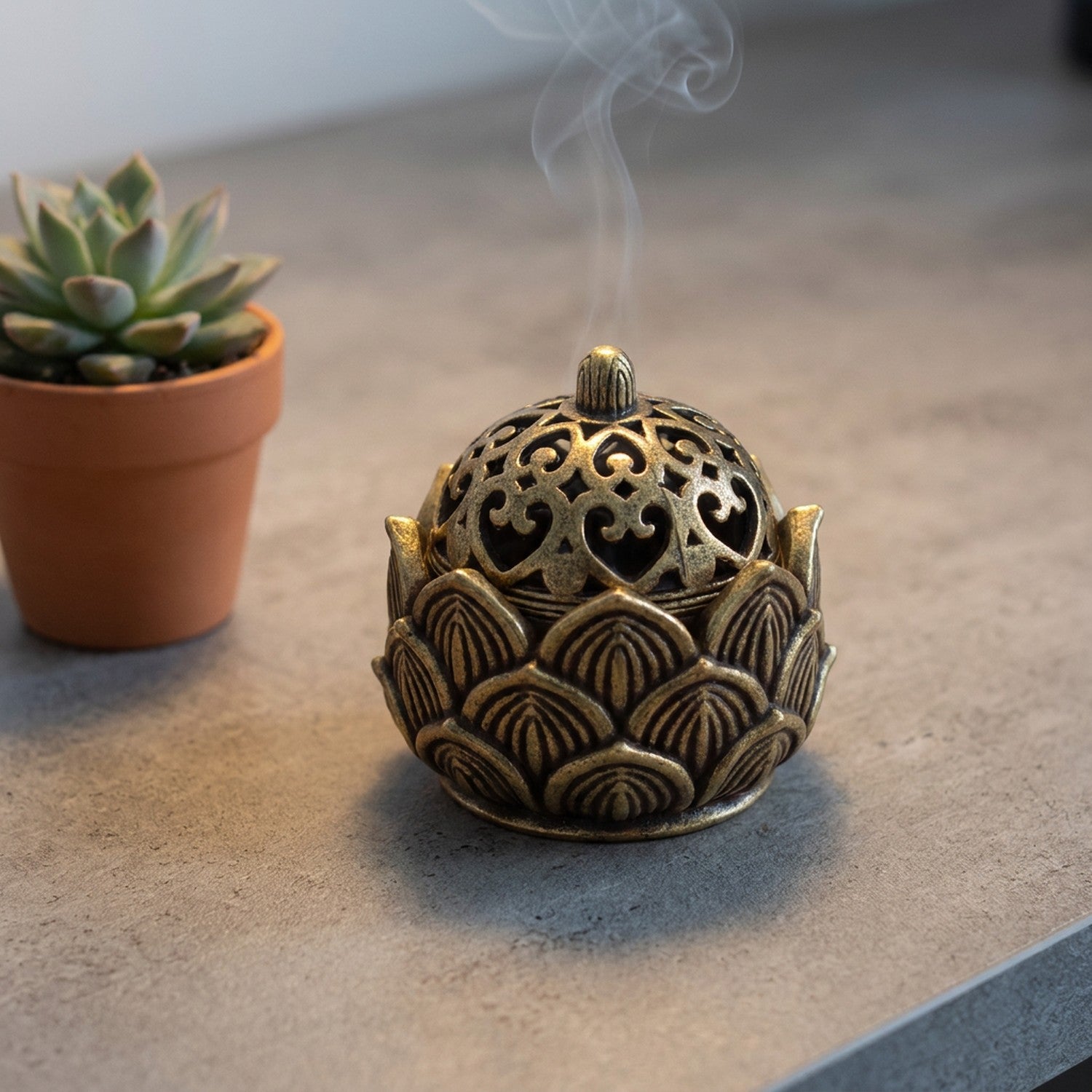 Brûleur d'encens lotus en laiton sur bureau béton avec plante grasse ambiance bureau zen