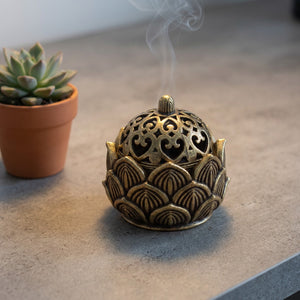 Brûleur d'encens lotus en laiton sur bureau béton avec plante grasse ambiance bureau zen