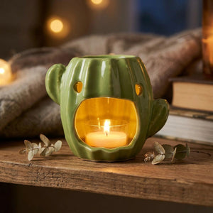 Brûle-parfum cactus en céramique vert clair avec une bougie allumée posé sur une étagère