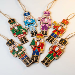Douze pendentifs casse-noisette en bois colorés suspendus à un sapin de Noël décoré de boules rouges